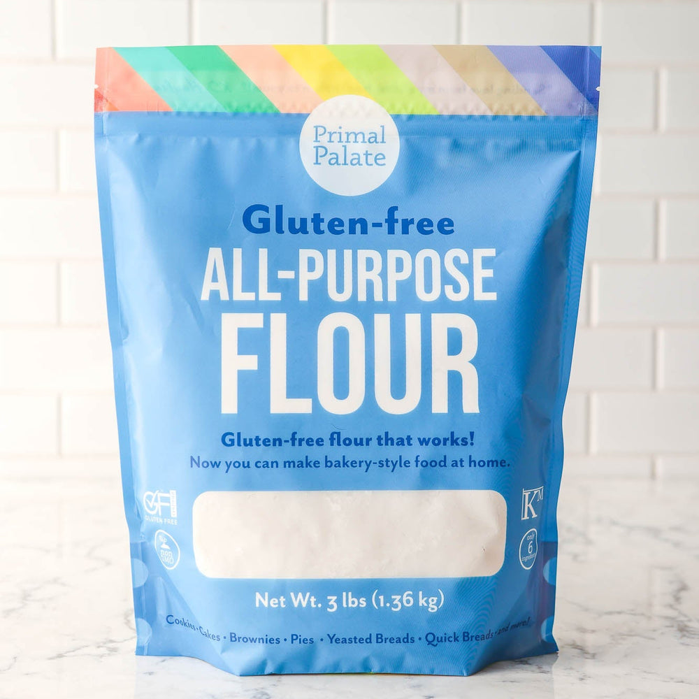 Bag of Primal Palate gluten-free all-purpose flour on a marble surface with a white tiled wall background.